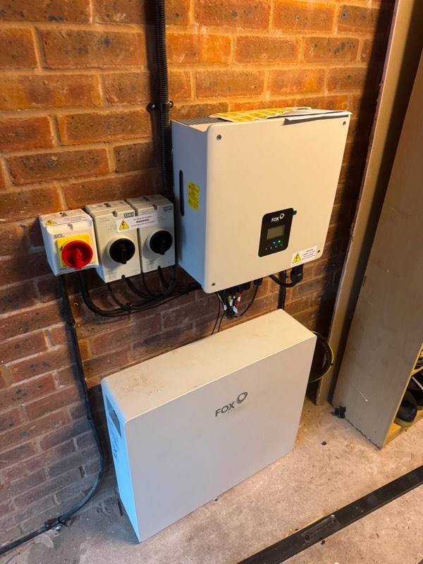 Fox ESS inverter and battery storage unit wall-mounted in a garage with isolators and conduit neatly run