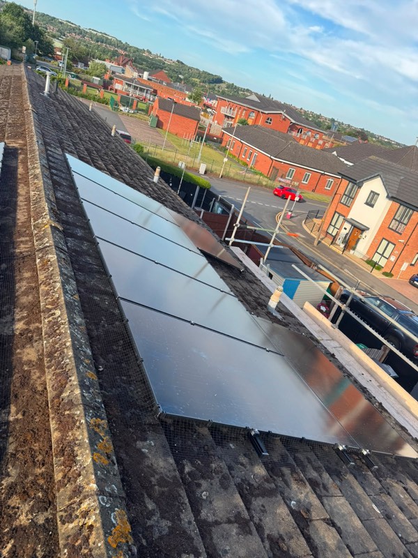All-black solar panels installed across a tiled roof with bird protection mesh fitted along the edge